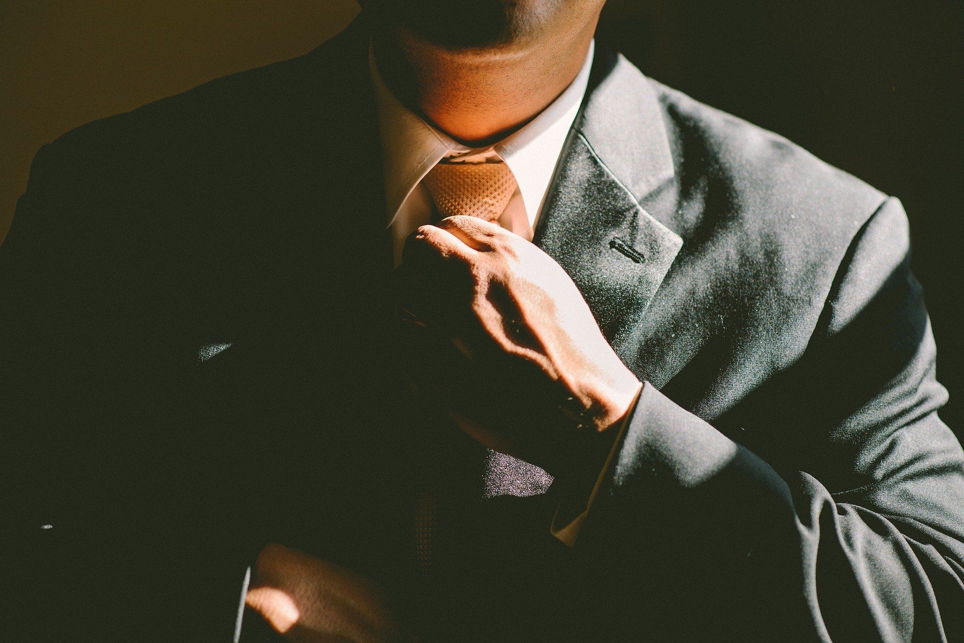 Ein Bildausschnitt zeigt einen Mann, der sich die Krawatte richtet.