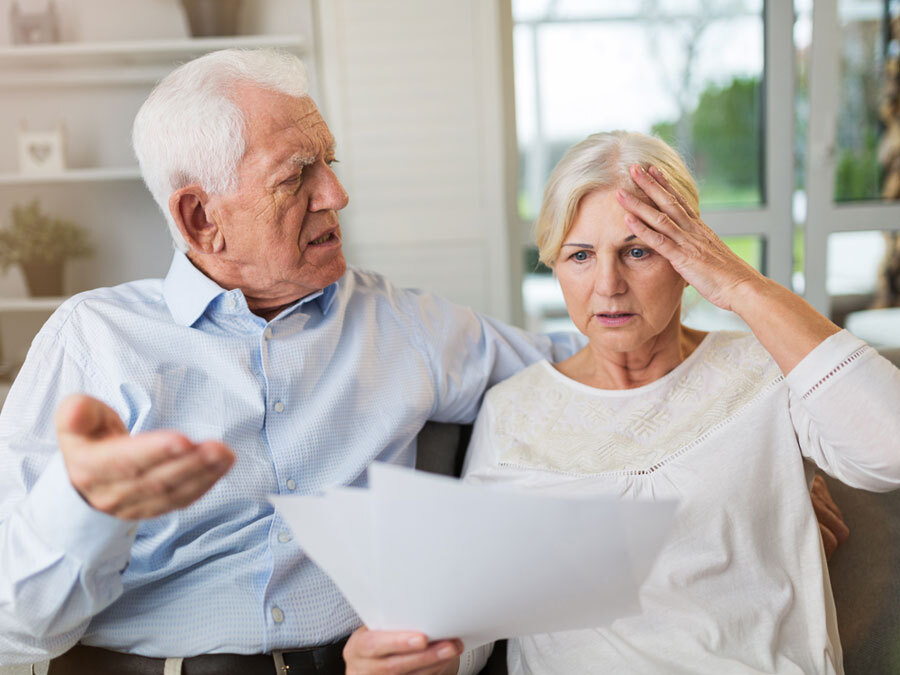 Großeltern lesen ein Schreiben und machen entsetzte Gesichter. Sie sollen Unterhalt für ihre Enkel zahlen.