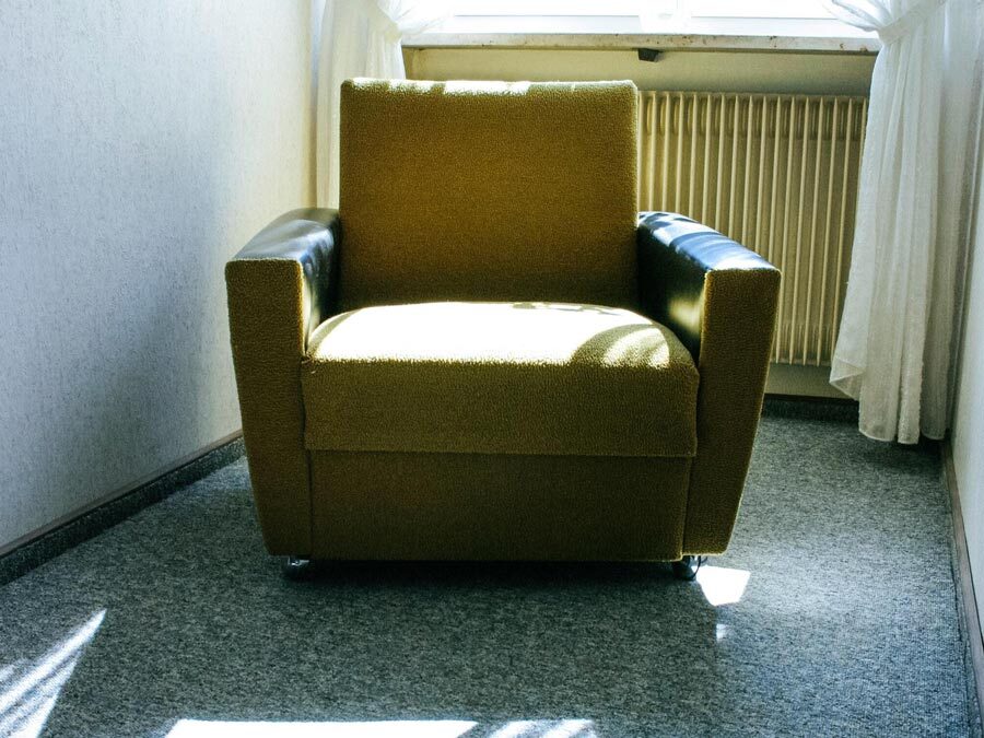 Ein alter Sessel steht in einem Abstellraum.