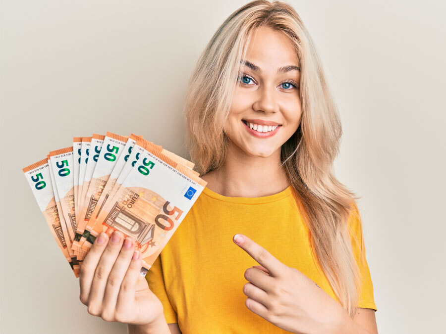 Eine Frau mit gelben T-Short hält viele Geldscheine in der Hand und lacht dabei.