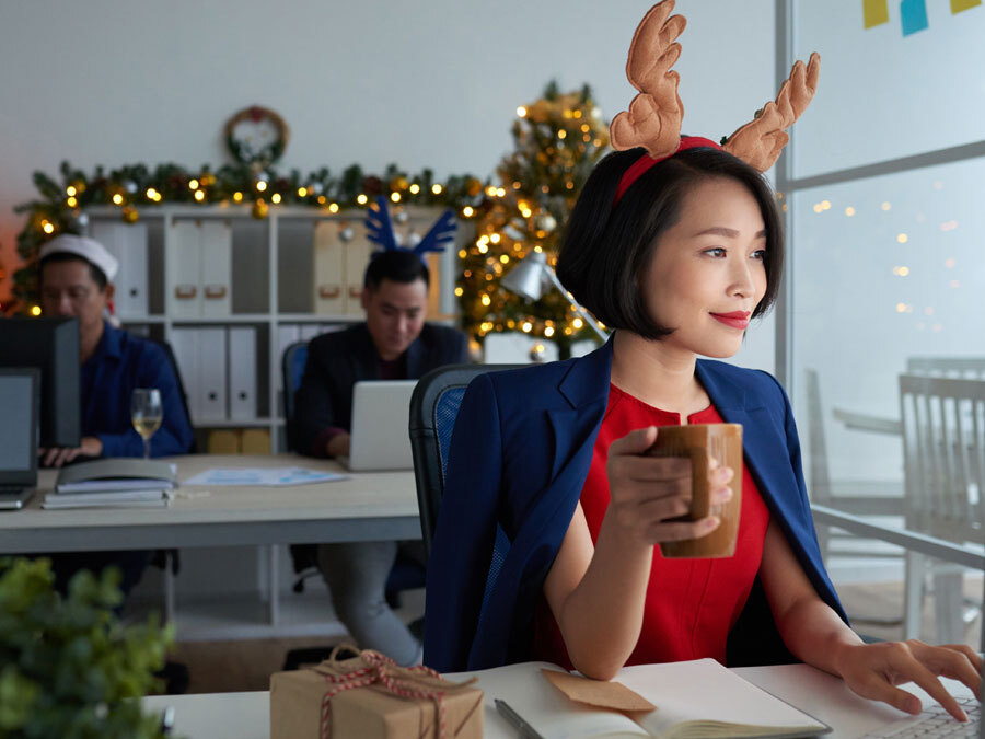 Ein weihnachtlich dekoriertes Büro und eine Frau, die arbeiten muss.