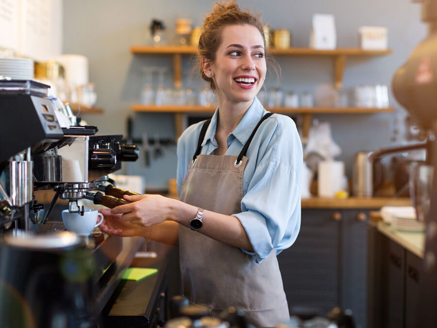 Eine Frau geht mit der Erlaubnis für einen Nebenjob einer weiteren Tätigkeit im Café nach.