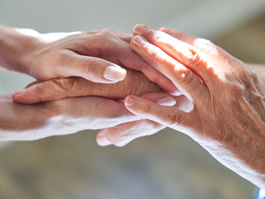 Die Hände einer jungen Frau halten die Hände einer älteren Frau.
