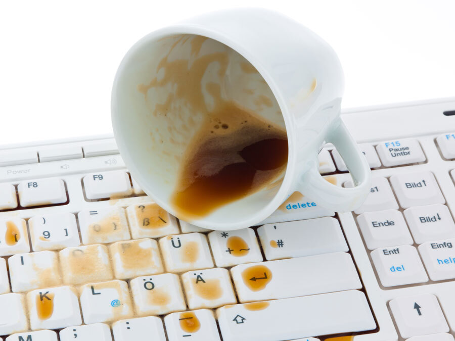 Kaffeetasse ist auf einer Tastatur ausgekippt.