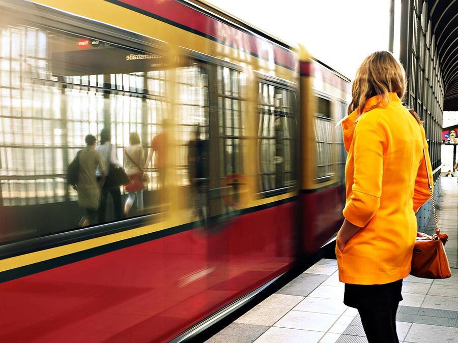 Eine Frau wartet auf die Bahn. Sie hat einen langen Arbeitsweg.