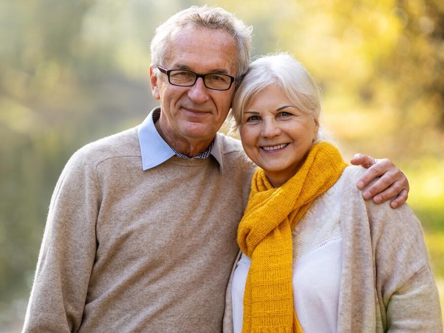 Ein älteres Ehepaar in herbstlicher Landschaft.