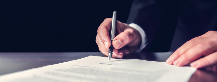 Ein Mann unterzeichnet sein Testament. Doch wie lange ist ein Testament gültig?