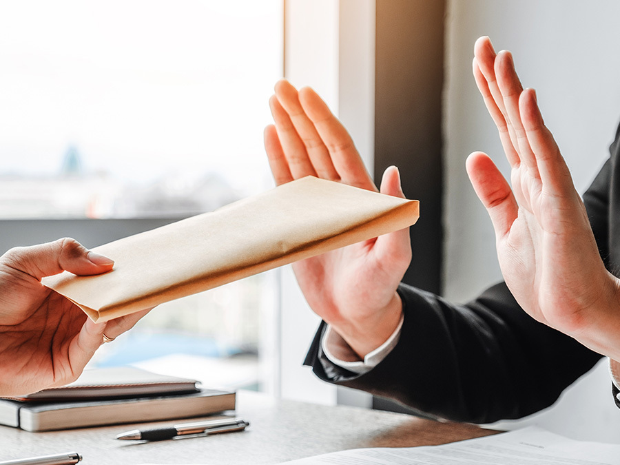 Ein Mann lehnt es ab einen Umschlag entgegenzunehmen. Er hält die Hände abwehrend hoch.