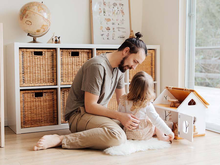 Ein Vater spielt mit seiner kleinen Tochter. Er ist zuhause und erhält Kinderkrankengeld.