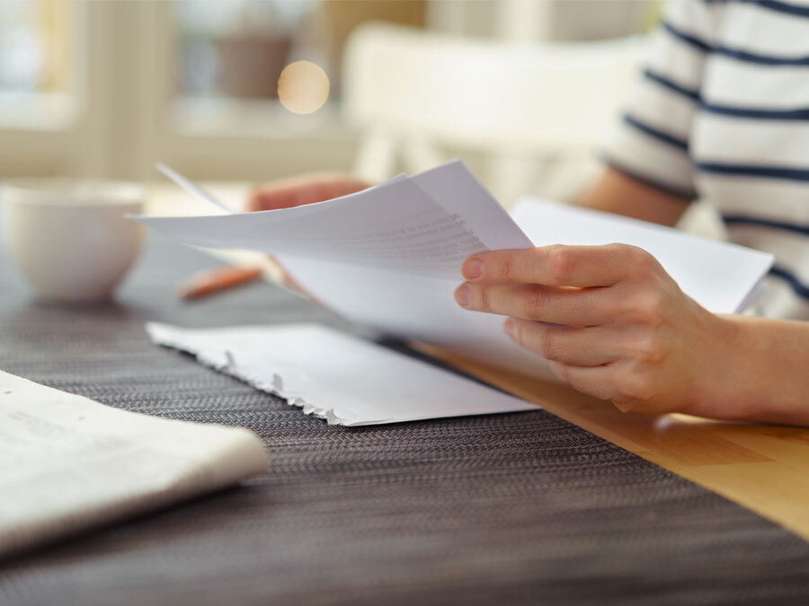 Eine Frau hält eine Betriebskostenabrechnung in Händen.