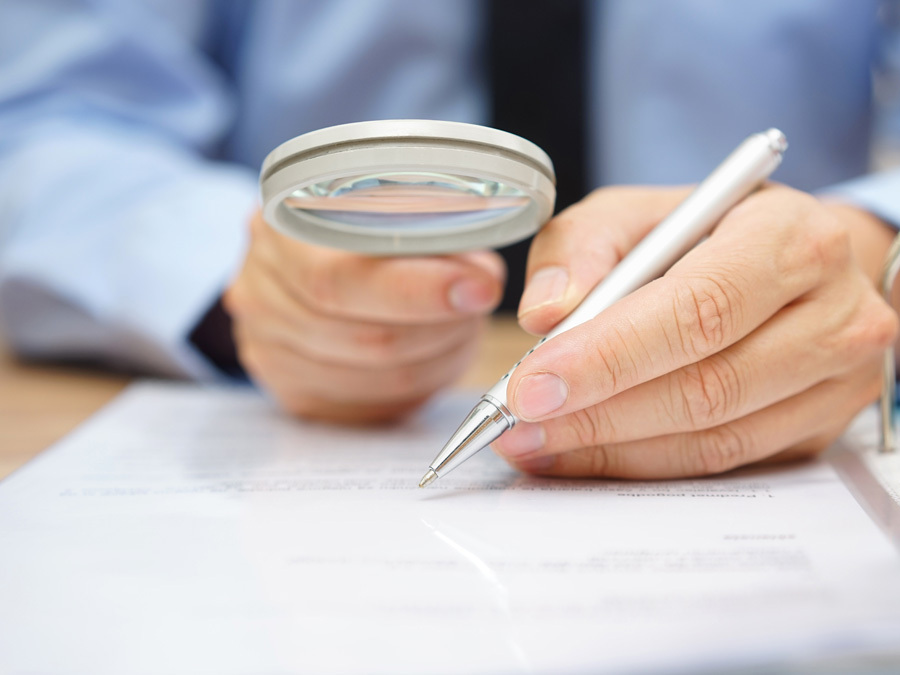 Ein Mieter prüft mit der Lupe die Zahlungsbelege für seine Betriebskostenabrechnung.