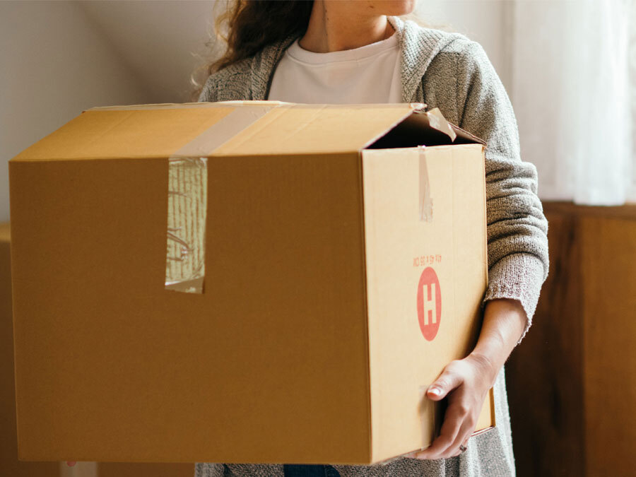 Eine Frau trägt eine Umzugskiste. Sie hat Eigenbedarf vorgetäuscht.