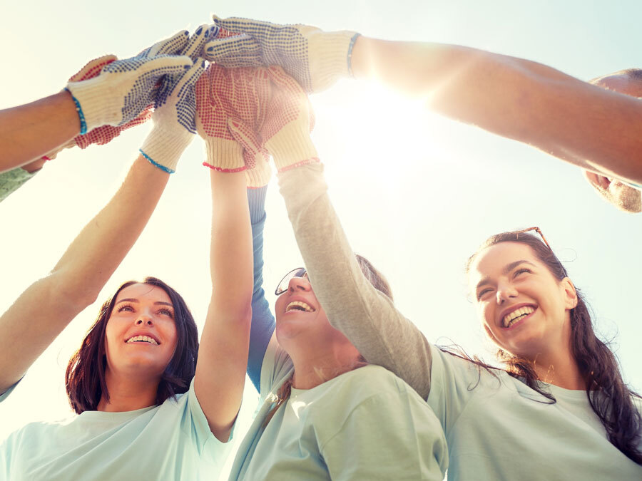 Eine Gruppe von Ehrenamtlichen vereint die Hände und freut sich, dass sie die Ehrenamtspauschale nutzen können