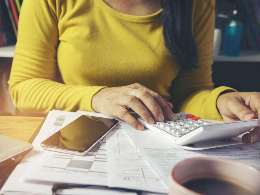 Eine junge Frau tippt auf einem Taschenrechner. Eine Studentin macht ihre Steuererklärung.