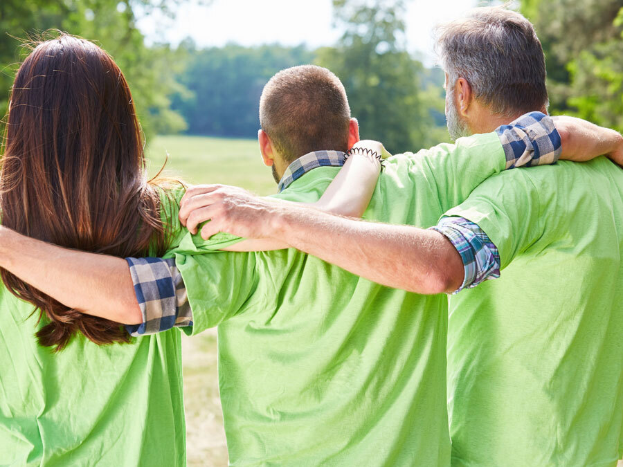 Drei Personen stehen mit dem Rücken zur Kamera und halten sich umschlungen. Die Drei leben in einer Wohngemeinschaft.