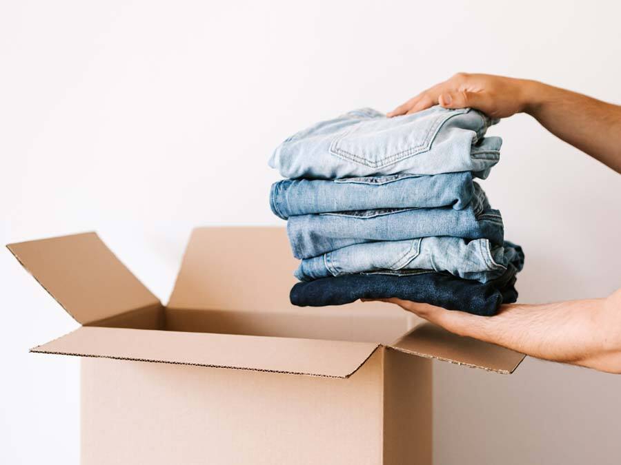 Ein Mieter packt seine Kleidung in eine Umzugskiste. Er hat seinen Zeitmietvertrag gekündigt.