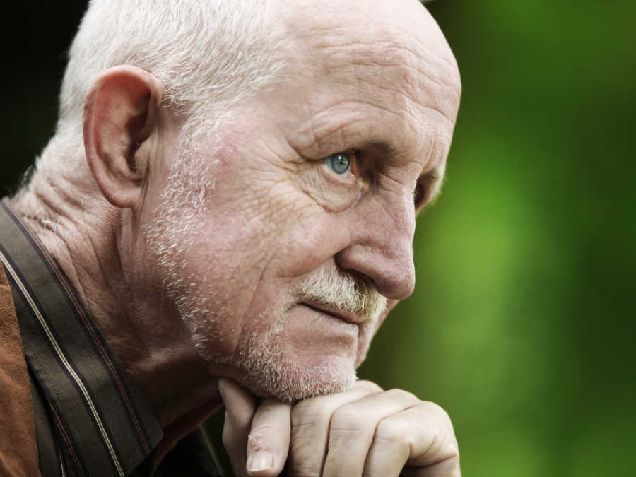 Ein älterer Herr schaut nachdenklich in die Ferne. Er beschäftigt sich gerade mit seiner Bestattungsverfügung.