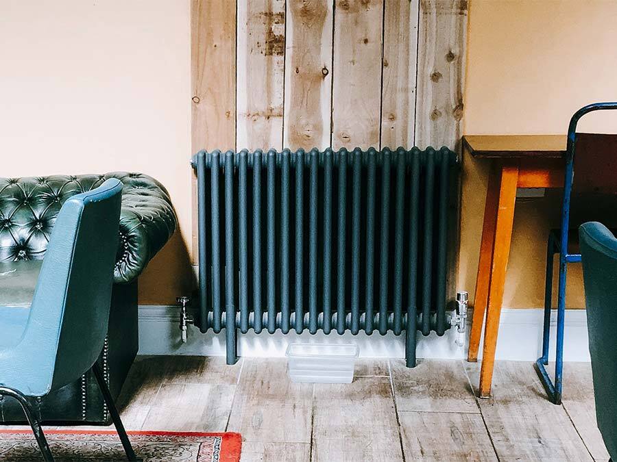 Ein blaugestrichener Heizkörper, der ein Leck hat. Wer ist für die Heizungswartung zuständig?