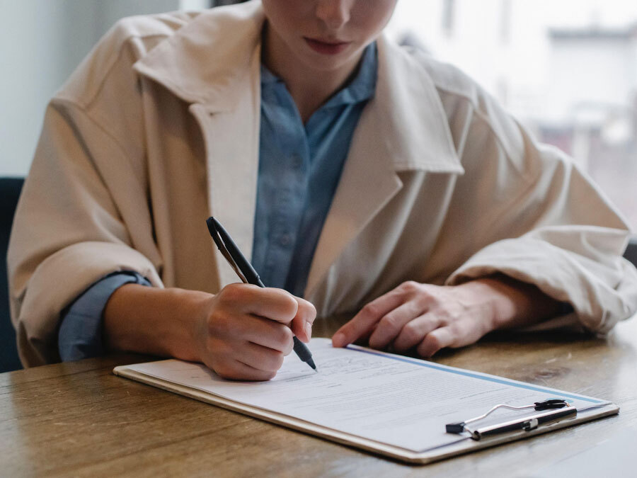 Ein neuer Mieter unterschreibt einen Mietvertrag. Damit ist die Übergabe des Mietvertrags besiegelt.