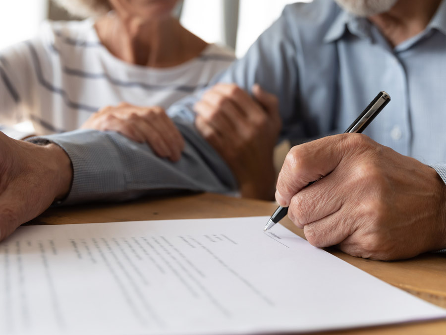 Ein Ehemann unterschreibt die Vollmacht für seine Frau.
