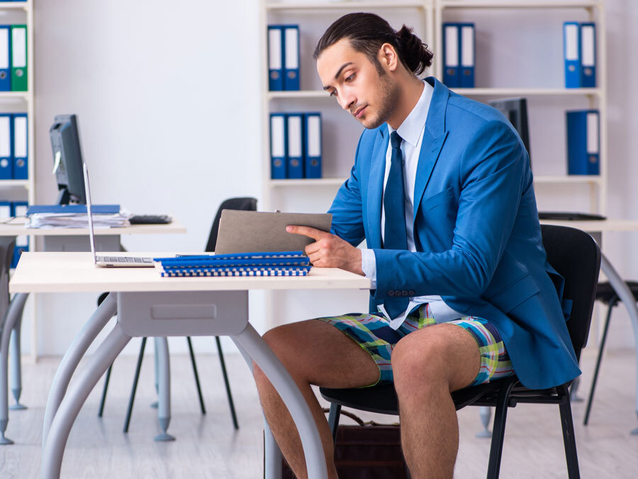 Ein Büroangestellter in Badehose im Büro. Die Arbeitskleidung ist nicht angemessen.