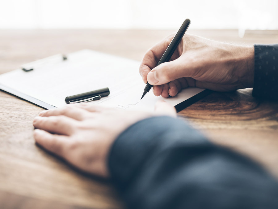 Mit dem Füller unterschreibt ein Mann sein Testament. Er sollte auch daran denken, das Datum im Testament neben die Unterschrift zu setzen.