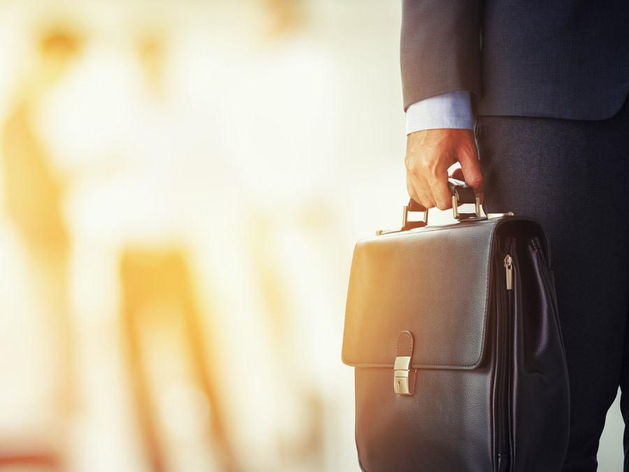 Ein Arbeitnehmer hält eine Aktentasche in der Hand. Er will eine Versetzung auf eigenen Wunsch durchsetzen.