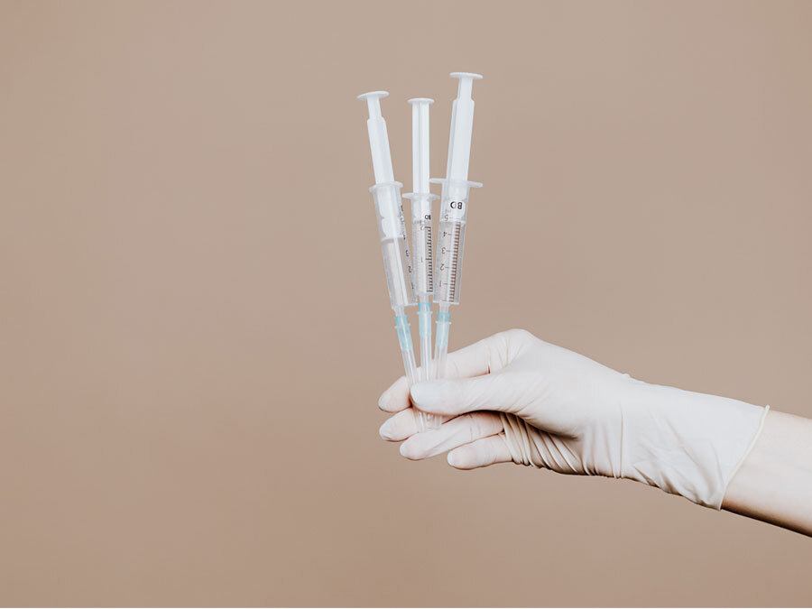 Drei Spritzen werden hochgehalten. Sie enthalten eine Impfung gegen Covid 19.