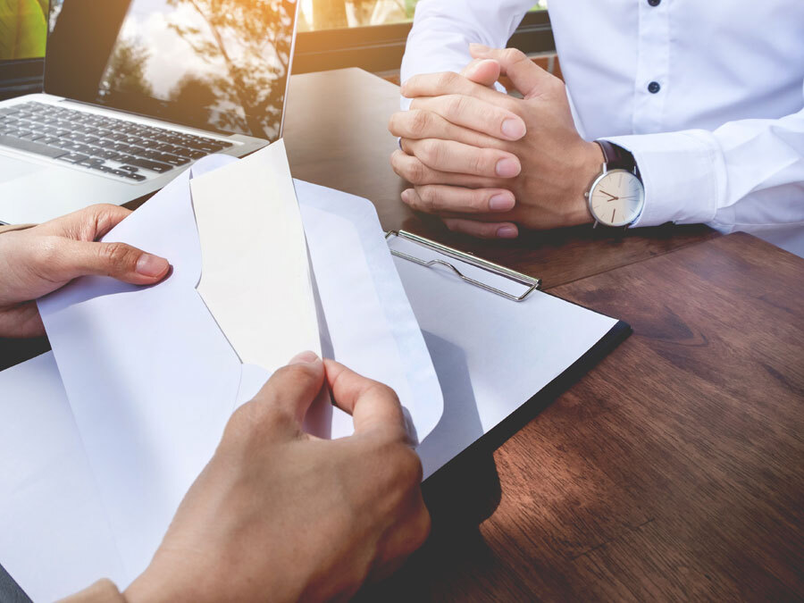 Jemand holt eine Kündigung aus dem Briefumschlag.