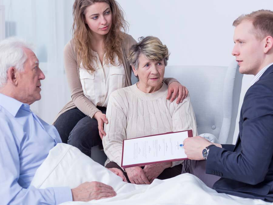 Ein schwerkranker Mann liegt im Krankenbett. Um ihn herum drei Personen. Sie errichten ein Nottestament.