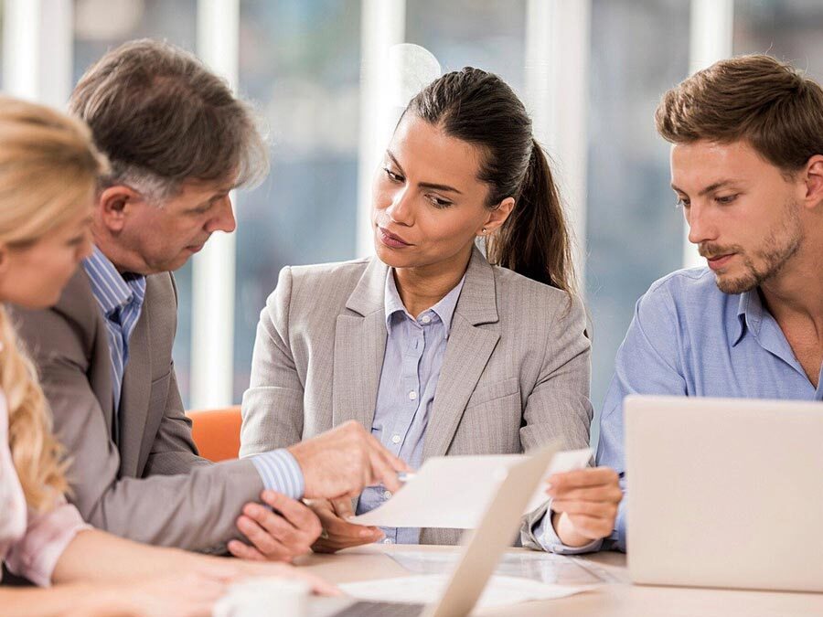 Ein Arbeitgeber und seine Mitarbeiterin führen ein Gespräch. Es handelt sich um jährliche Mitarbeitergespräche.
