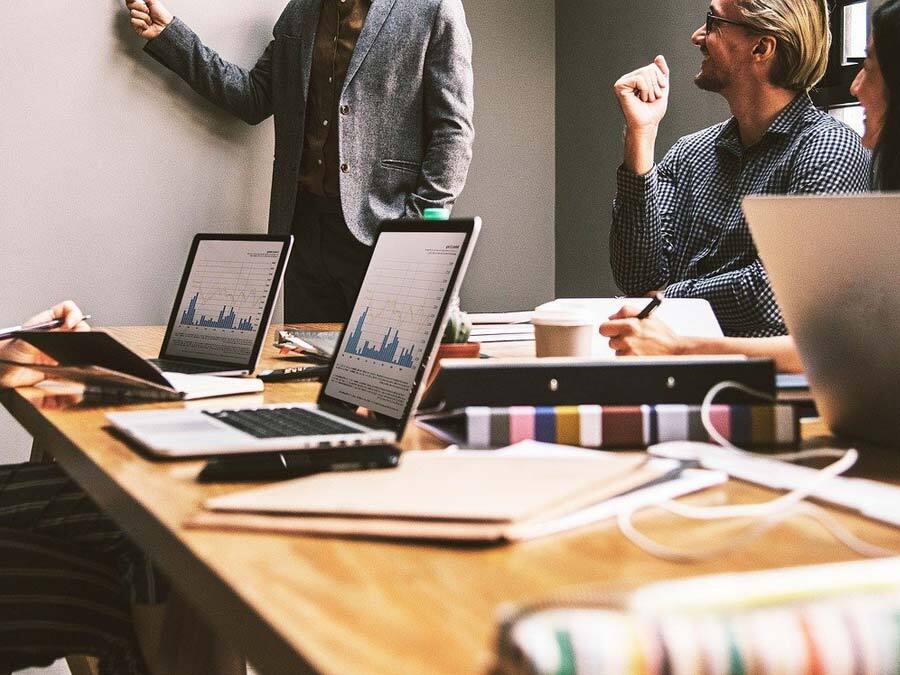 Zwei Laptops auf einem Schreibtisch und Arbeitsutensilien. Ein Team setzt sich SMART formulierte Ziele.