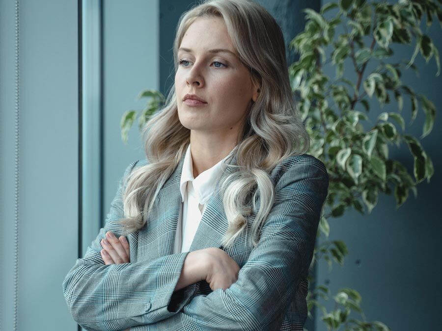 Eine Arbeitnehmerin mit verschränkten Armen und kritischem Blick. Ihr Chef beruft sich auf eine pauschale Überstundenabgeltung..