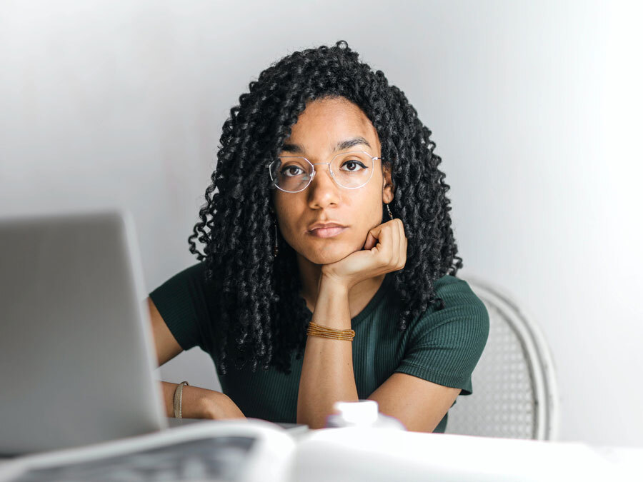 Eine Frau sitzt an ihrem Schreibtisch und kämpft mit anhaltender Unzufriedenheit im Job.