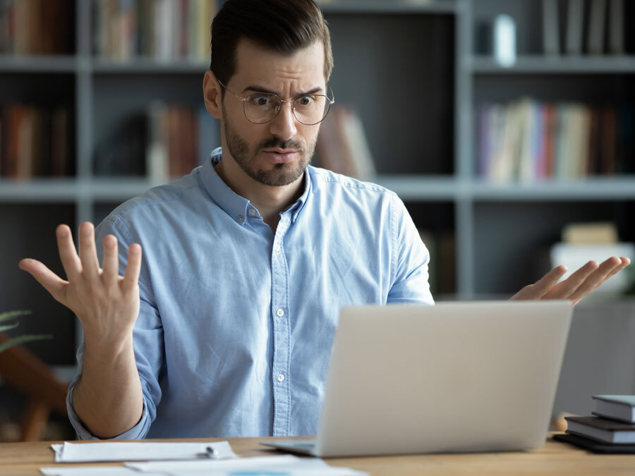 Ein Mann sitzt vor einem Laptop macht ein verzweifeltes Gesicht. Es gab eine Datenpanne.