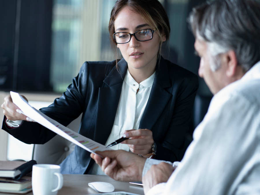 Eine Anwältin erklärt einem Mandanten den Unterschied zwischen Erbe und Vermächtnis.