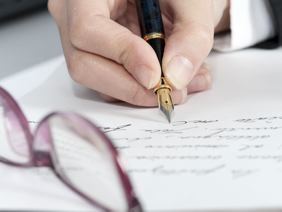 Eine Frau schreibt ein handschriftliches Testament. Hoffentlich vermeidet sie Fehler im Testament.