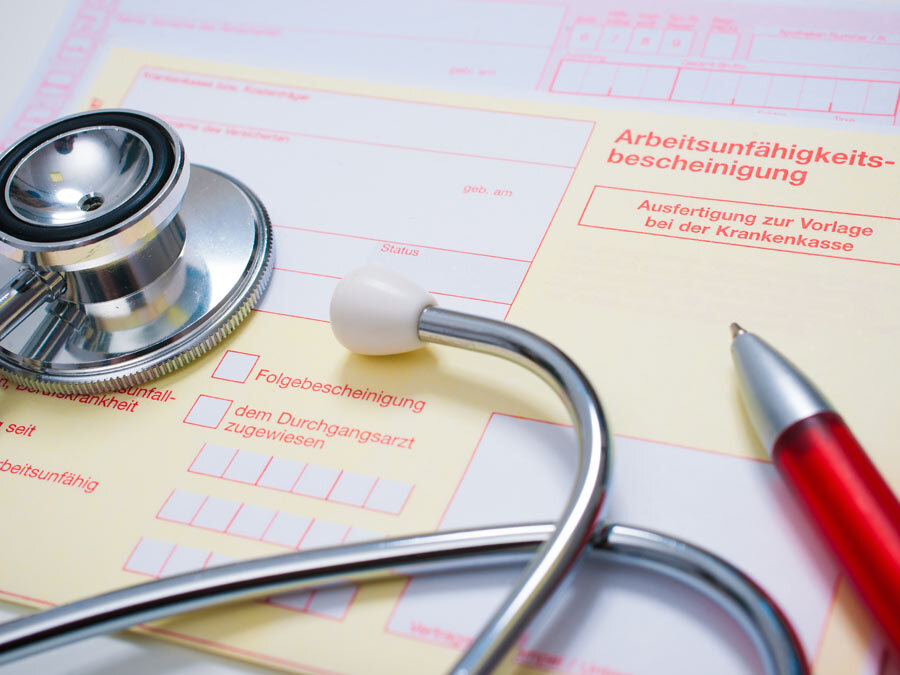 Eine Arbeitsunfähigkeitsbescheinigung liegt auf dem Tisch. Der Arbeitgeber möchte die Krankschreibung prüfen.