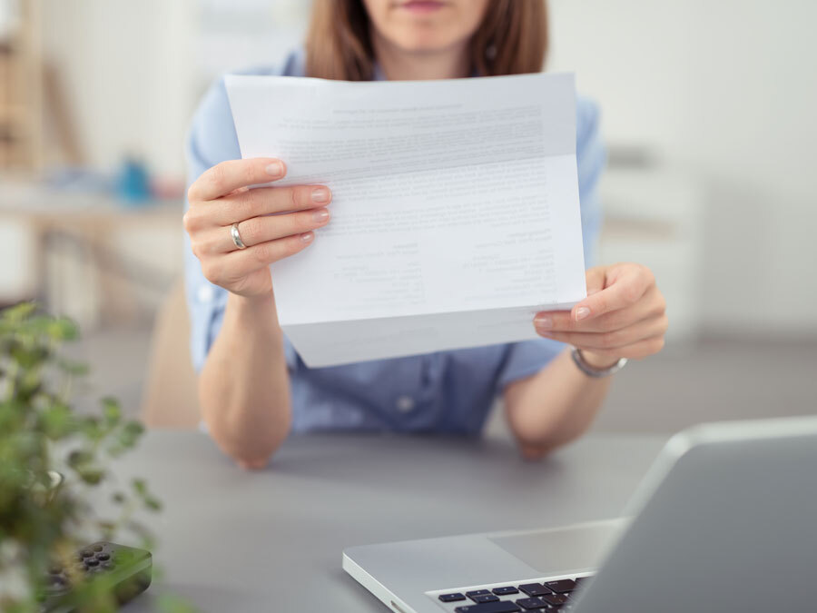 Eine Frau hält einen ernsten Brief in den Händen. Es ist eine Mahnung wegen Zahlungsverzug.