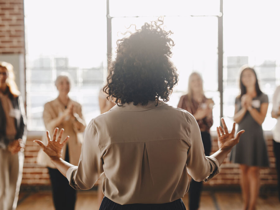Ein Coach steht vor einer Gruppe von Klienten, mit welcher Sie einen Coaching Vertrag abgeschlossen hat