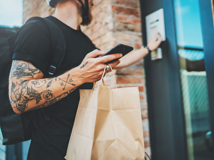 Ein Lieferant klingelt an einer Haustür. Er ist mit einem Dienstrad gekommen.