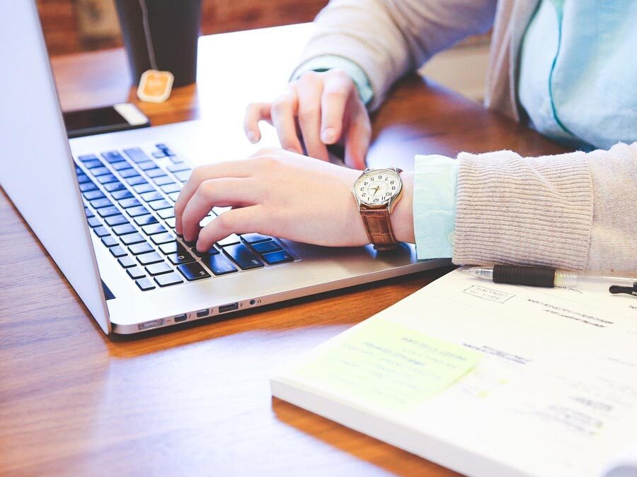 Eine Frau tippt in ihren Laptop. Sie will die Steuer-ID bei Minijobs melden.