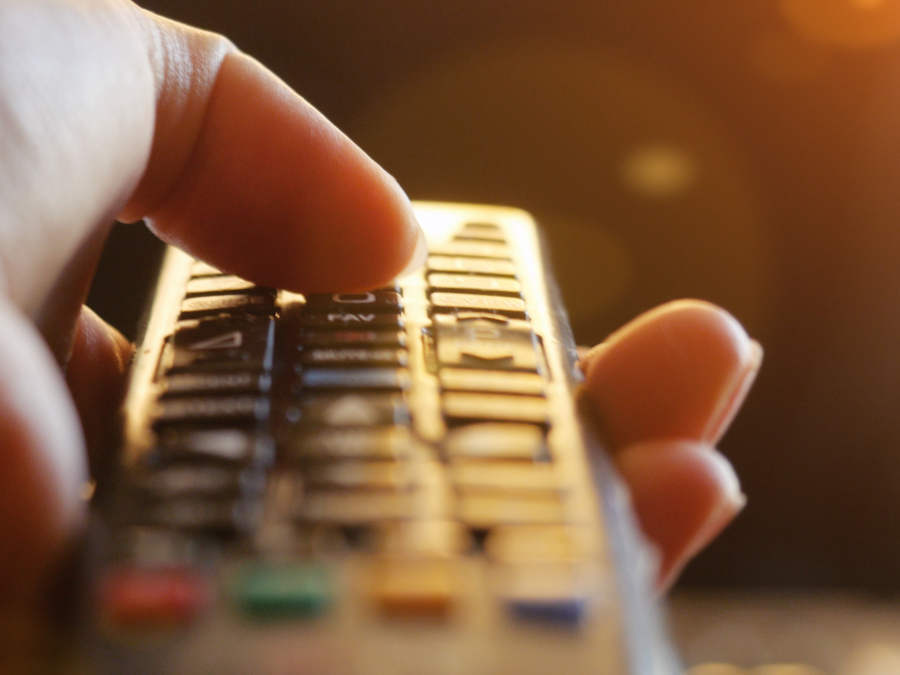 Eine Nahaufnahme der Hand einer Frau mit einer Fernbedienung in der Hand.