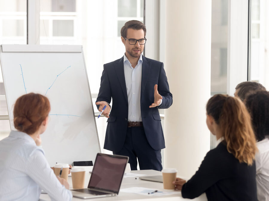 Ein Mann arbeitet selbstständig als Coach und steht an einem Flipchart