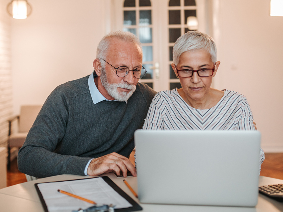 Ein Paar sitzt vor einem Laptop und hat daneben ein Formular Untervollmacht zu liegen.