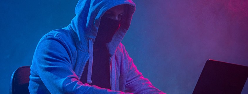Ein maskierter Mann sitzt vor einem Rechner.