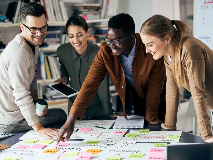 Vier Personen arbeiten zusammen an einer Mindmaps, um die Kreativität im Unternehmen zu fördern