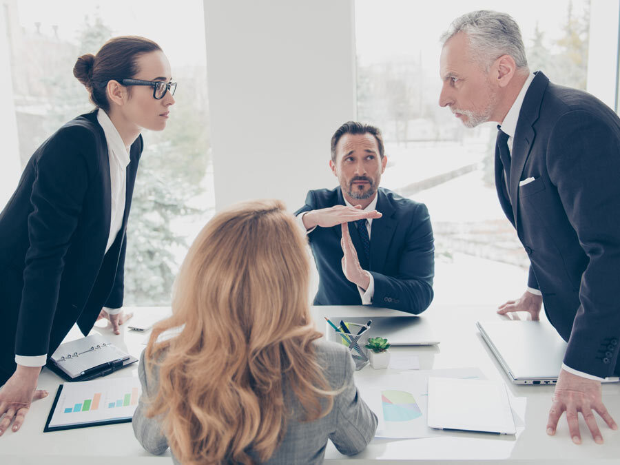 Vier Kollegen tragen untereinander Konflikte am Arbeitsplatz aus.