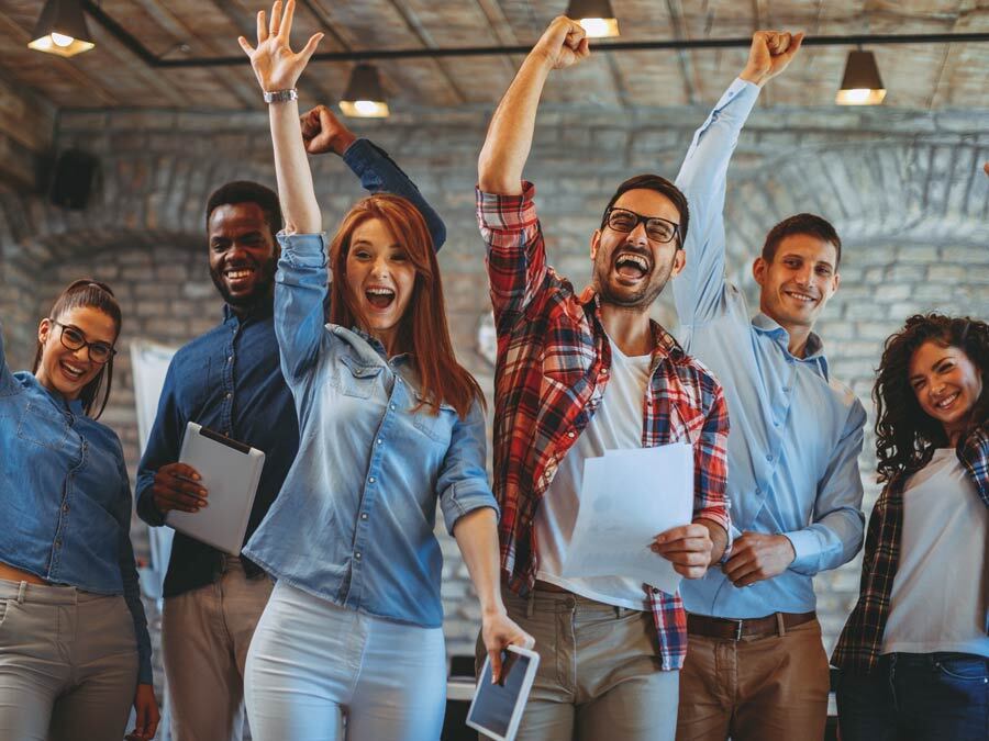 Mehrere Arbeitnehmer freuen sich über die extrinsische Mitarbeitermotivation ihres Arbeitgebers.