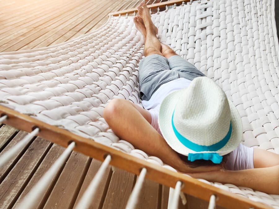 Ein Mann liegt auf einer Hängematte und genießt seinen unbezahlten Urlaub, da er sich bereits um seine Krankenversicherung gekümmert hat.